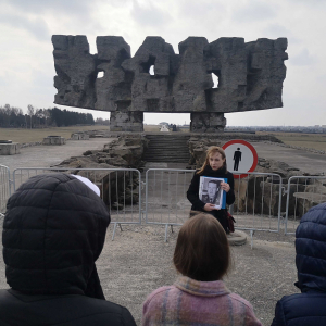 Uczniowie klasy siódmej z opiekunkami i przewodnikiem przed bramą główną Muzeum na Majdanku