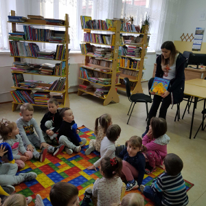 Wizyta dzieci z grupy młodszej w bibliotece publicznej- Pani Kasia przedstawia pracę bibliotekarza