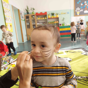 Światowy Dzień Kota w grupie młodszej - malowanie buziek przez wychowawczynię 