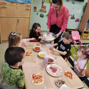 Przedszkolaki nakładają sos na pizzę