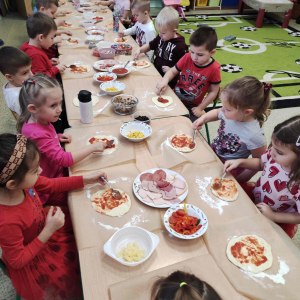 Przedszkolaki nakładają sos na pizzę