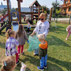 Dzieci z grup starszej i średniej sprzątają plac zabaw