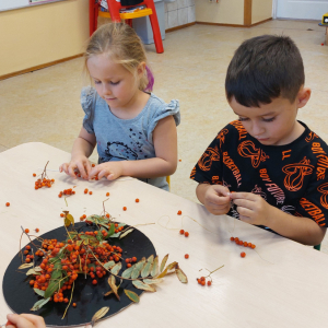 Dzieci nawlekają korale z jarzębiny