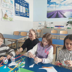 Praca zespołowa i kreatywność w akcji! Uczennice klasy czwartej podczas zajęć technicznych z dumą prezentują swoje kolorowe prace z papieru, doskonaląc zdolności manualne i wyobraźnię przestrzenną.
