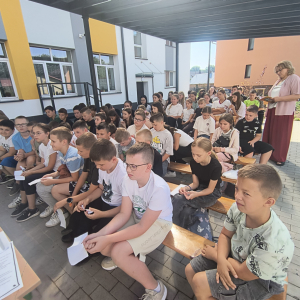 Narodowe Czytanie 2025 - uczeniowie słuchają utworów czytanych przez koleżanki.