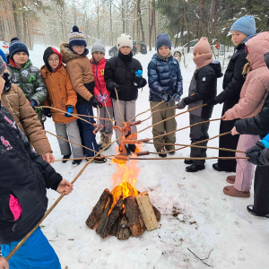 Uczniowie klas czwartych i piątej przy ognisku podczas pieczenia kiełbasek